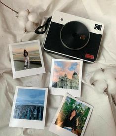 polaroid camera sitting on top of a bed next to pictures and cotton floss