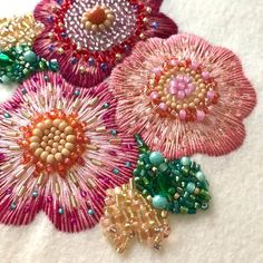 several different colored beaded flowers on a white surface