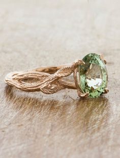 a green ring sitting on top of a wooden table next to a leaf shaped object