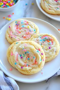 three cookies with sprinkles on a white plate