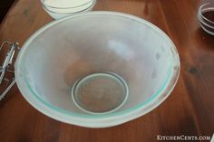 a glass bowl sitting on top of a wooden table next to two empty bowls and measuring spoons