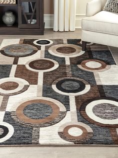 an area rug with various circles and shapes on it in a living room, next to a white chair