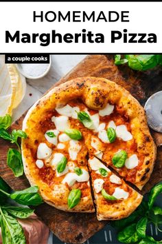 a pizza sitting on top of a wooden cutting board next to basil leaves and cheese