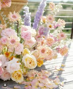 a bunch of flowers sitting on top of a wooden table next to other flowers and confetti