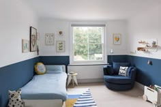 a bedroom with blue walls and furniture in the corner, along with a large window