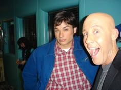 two men standing next to each other in front of a mirror with one man's face painted on it