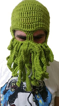 a man wearing a green knitted hat with an octopus like creature on it's face