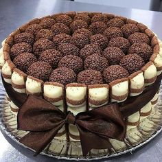 a chocolate cake with white frosting and brown bows on it's edges, sitting on a plate