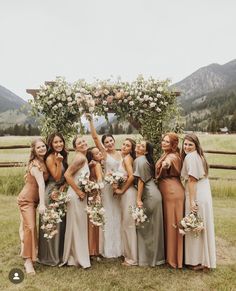 a group of women standing next to each other in front of a lush green field