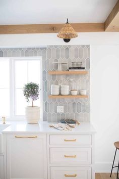 a kitchen with white cabinets and gold pulls on the doors, shelving above the counter