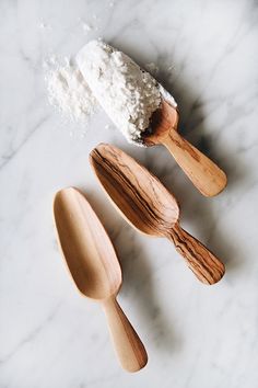 three wooden spoons and two scoops with powdered sugar on them sitting next to each other