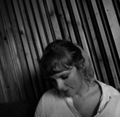 black and white photograph of a woman looking at her cell phone in front of a wooden wall