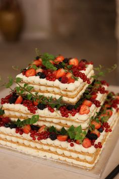 a three layer cake with strawberries, raspberries and blueberries on top