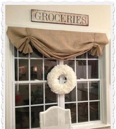 a white chair sitting in front of a window with a wreath on top of it