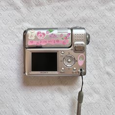 an old camera with hello kitty stickers on it's side sitting on a bed