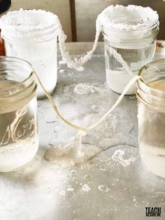 three jars filled with white powder sitting on top of a table