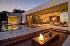 an outdoor living area with a fire pit and lounge chairs next to the swimming pool