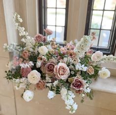 an arrangement of flowers in front of two windows