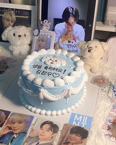 a table topped with a cake covered in frosting next to pictures and teddy bears