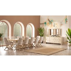 a dining room table and chairs with an area rug in front of the window that has arched windows