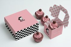 three pink cupcakes are in a box with checkers on the side and one is inside