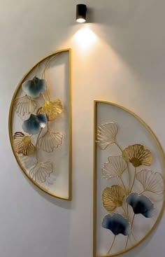 the wall is decorated with gold and blue flowers on white walls, along with two circular metal art pieces