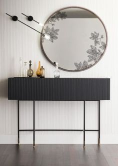 a black and white console table with a round mirror on it's sideboard