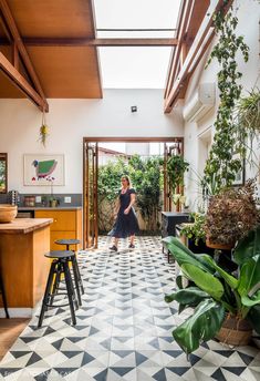 a woman is standing in the middle of a room with plants and potted plants