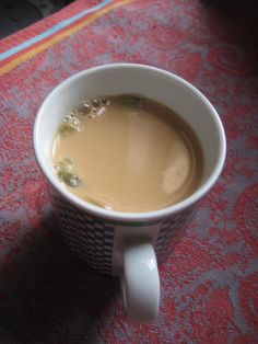 a cup of coffee sitting on top of a red tablecloth next to a cell phone