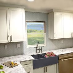 a kitchen with marble counter tops and white cabinets, along with stainless steel dishwashers