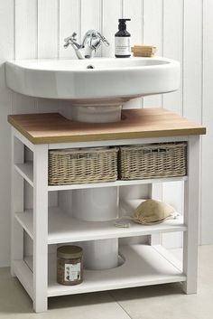 a white sink sitting next to a wooden shelf with baskets on it's sides