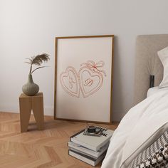 a bedroom with a bed, nightstand and framed artwork on the wall next to it