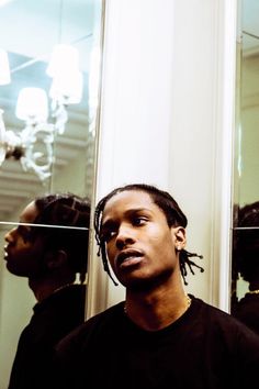 a man with dreadlocks standing in front of a mirror