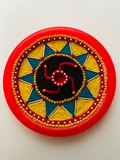 a red and yellow painted object on a white surface with the letter s in it's center