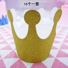 a gold crown sitting on top of a pink and white checkered tablecloth with chinese characters in the background