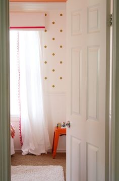 an open door leading to a bedroom with polka dots on the walls and carpeted floor