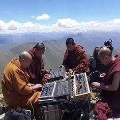 four monks sitting on top of a mountain with sound equipment in their hands and looking at the camera