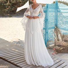 a woman in a white dress standing on a wooden platform with her arms around her waist