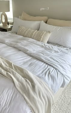 a large bed with white sheets and pillows