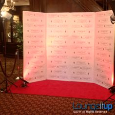 a red carpeted area with a white backdrop and microphone set up for a press conference