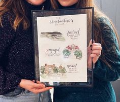 two women holding up a framed poster with their names on it and the words congratulations written below them