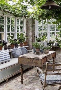 an outdoor patio with lots of potted plants on the table and chairs around it