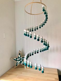 a white and blue mobile hanging from the ceiling next to a wooden table with a star on it