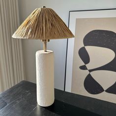 a lamp sitting on top of a wooden table next to a painting and an art piece