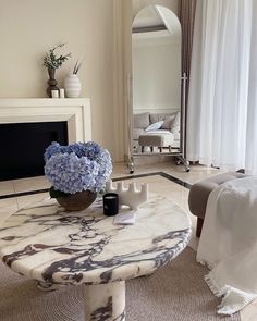 a living room with a marble coffee table and blue flowers