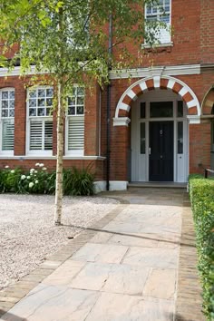 a brick building with white trim and arched windows on the front door, along with a stone walkway leading up to it