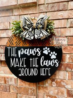 a sign that says the paws make the paws around here with a bow on it