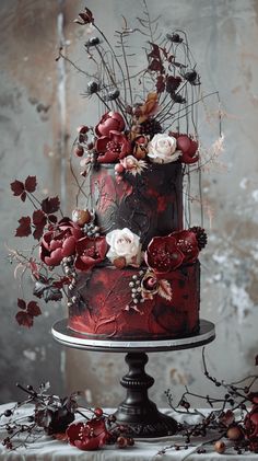 a red and black wedding cake with flowers on the top is sitting on a table