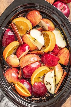 apples, oranges and cinnamon sticks are in the slow cooker for apple cider