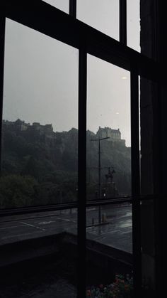 the view from an open window looking out at a castle on top of a hill